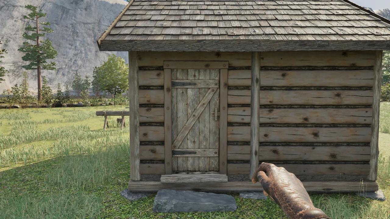 The front of a log cabin up close, a plank door with a Z-brace and iron strap hinges, a split-log threshold and a flat stone step, a sawbuck in the meadow behind